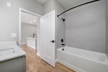 A white bathroom with a tub, sink and shower head at Ironwood Flats Apartments, Brandon, FL, 33511